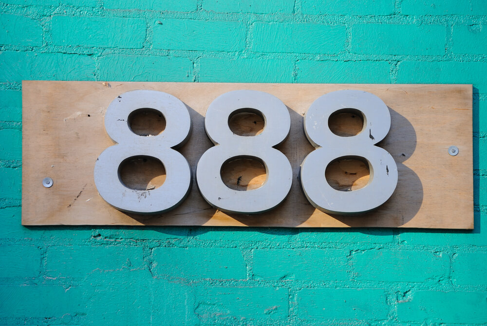 An address 888 on a turquoise brick wall. 