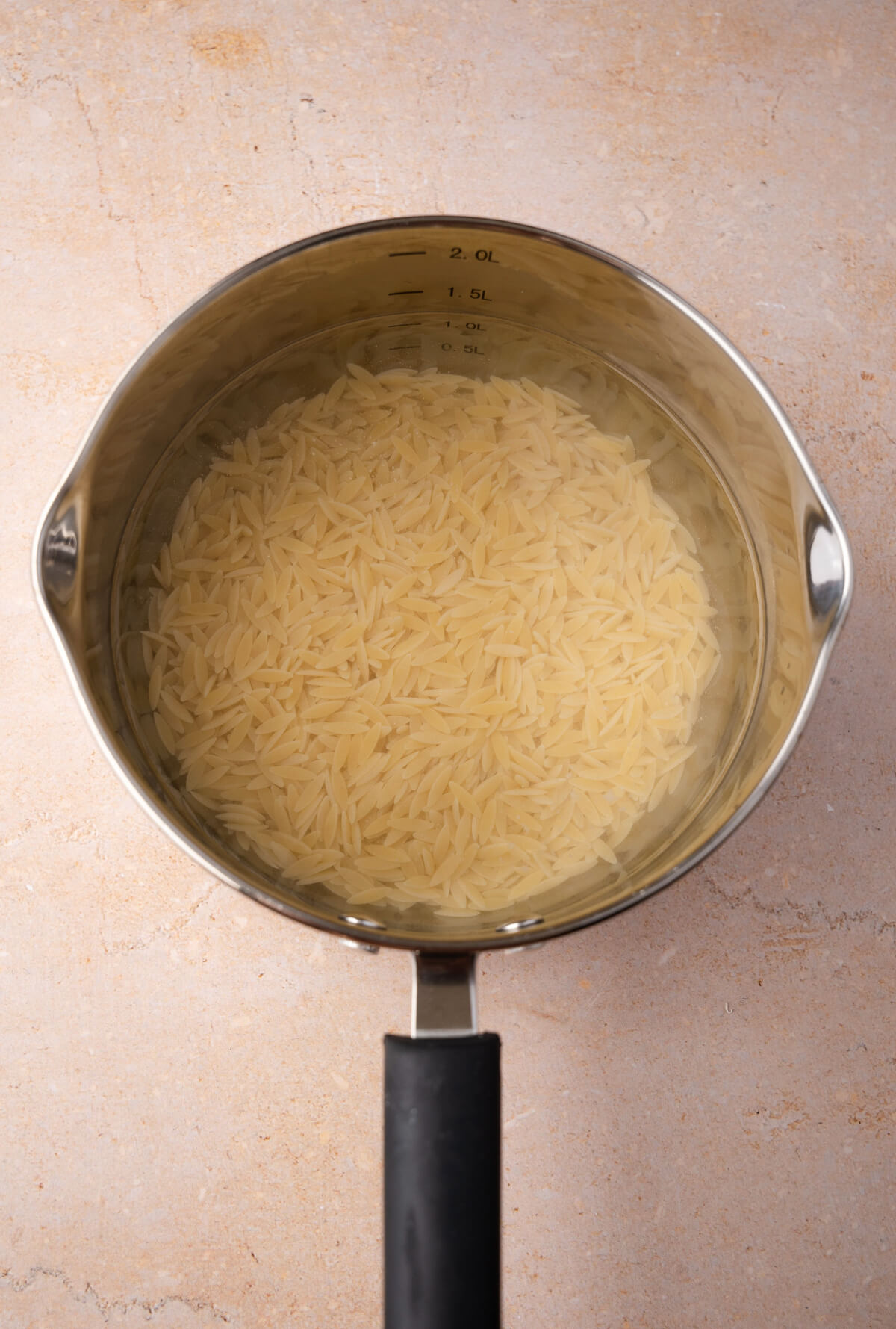 A small saucepan filled with water and orzo pasta.