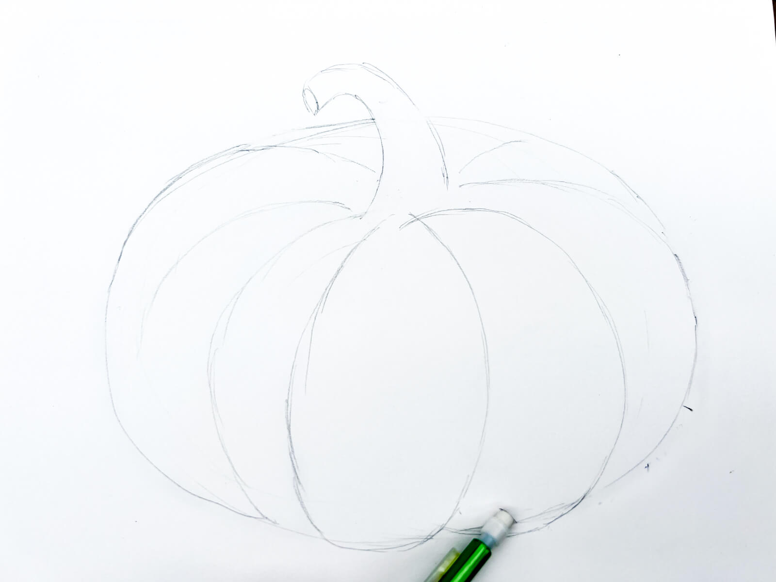 An eraser removes sketch marks from a hand drawn pumpkin.