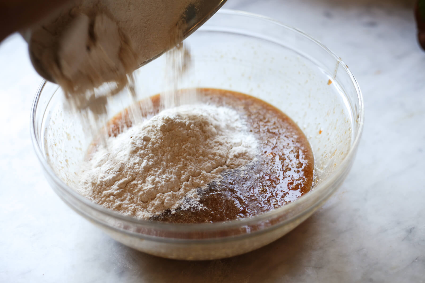 Dry ingredients are added to wet ingredients to make persimmon bread.