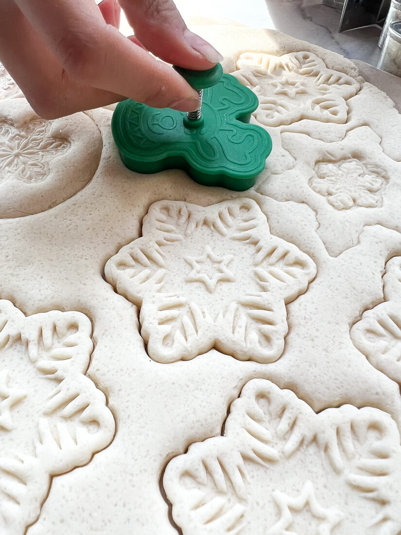 A cookie cutter is pressed into salt dough.