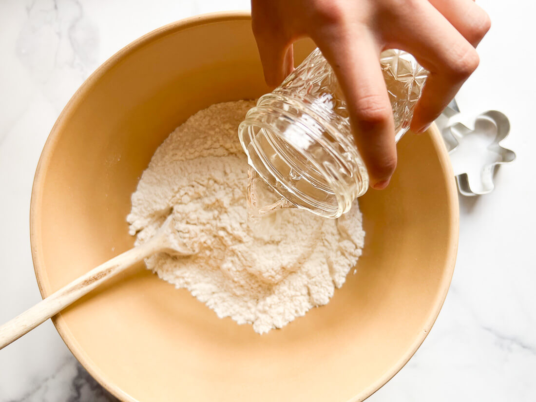 Water is added to flour and salt in a ceramic bowl.