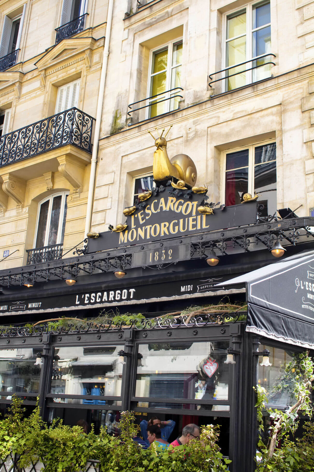 The front of L'Escargot Montorguel in Paris France. The building sign is topped with a golden snail. Classic French restaurant. 