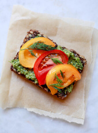 Seed bread slice topped with pesto and tomatoes.