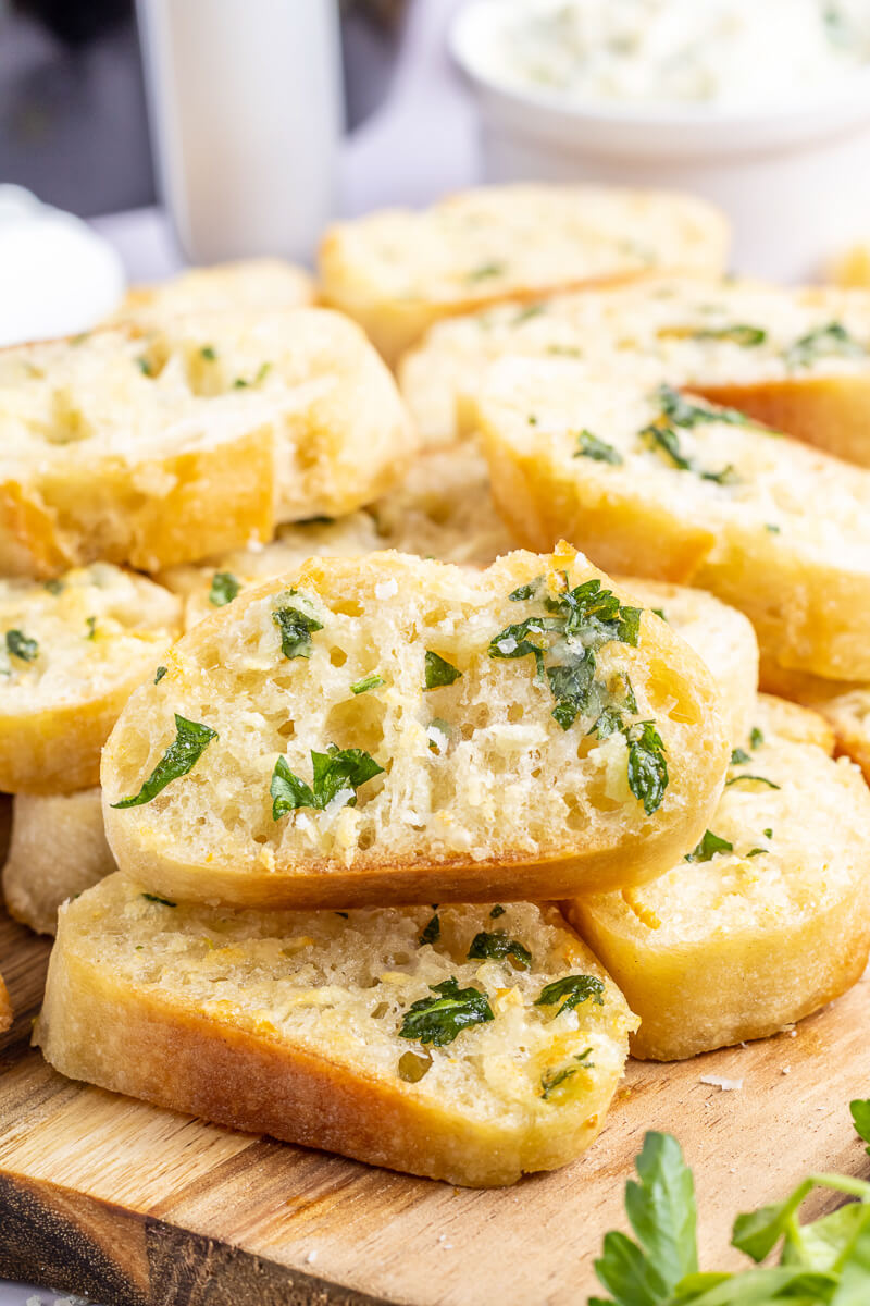 A mouthwatering photo of slices of garlic bread made with slices of baguette and parsley. 