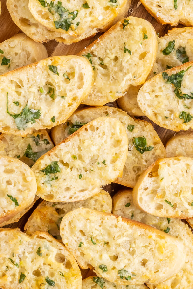 Slices of crisp baguette garlic bread made with garlic butter and parsley. 