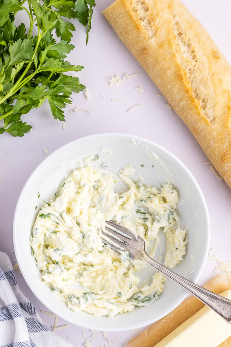 The ingredients for garlic bread spread are mixed together in a white bowl.