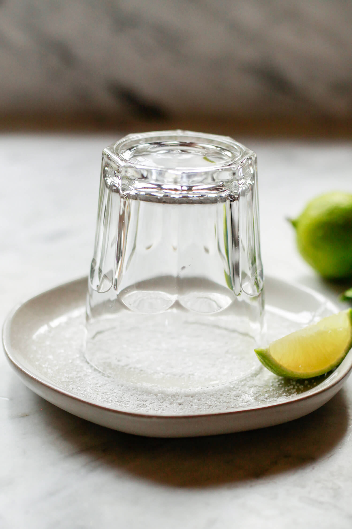 A rocks glass inverted on a small dish of salt with a lime on the side. This is how you make a salt rim for a Cadillac Margarita. 