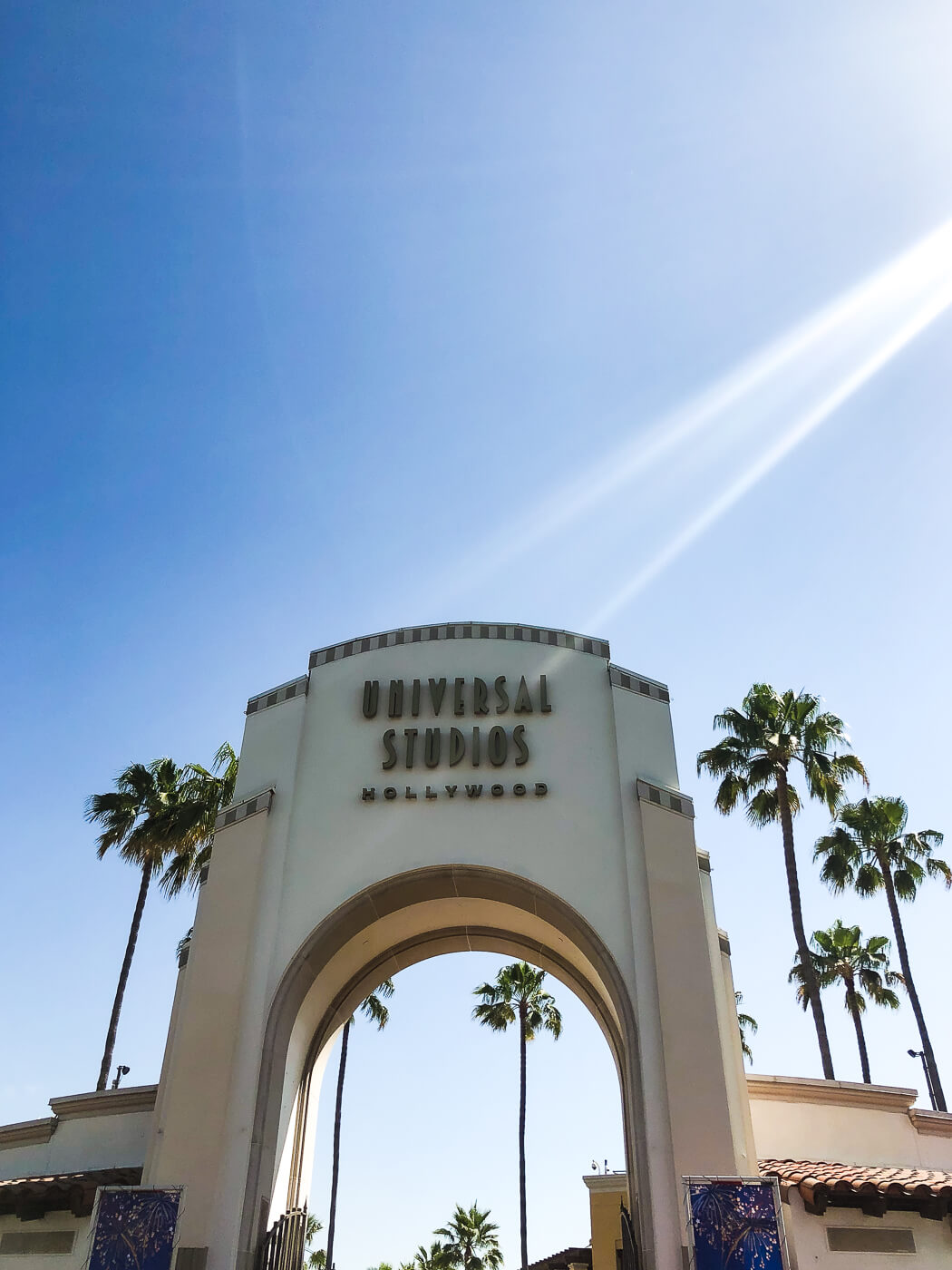 The iconic arched entrance to Universal Studios Hollywood with palm trees in the background. 