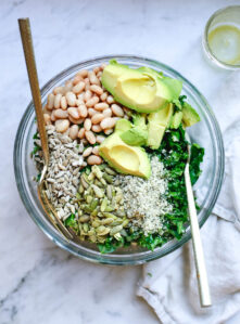 Overhead photo of kale and white bean salad with avocado and seeds.