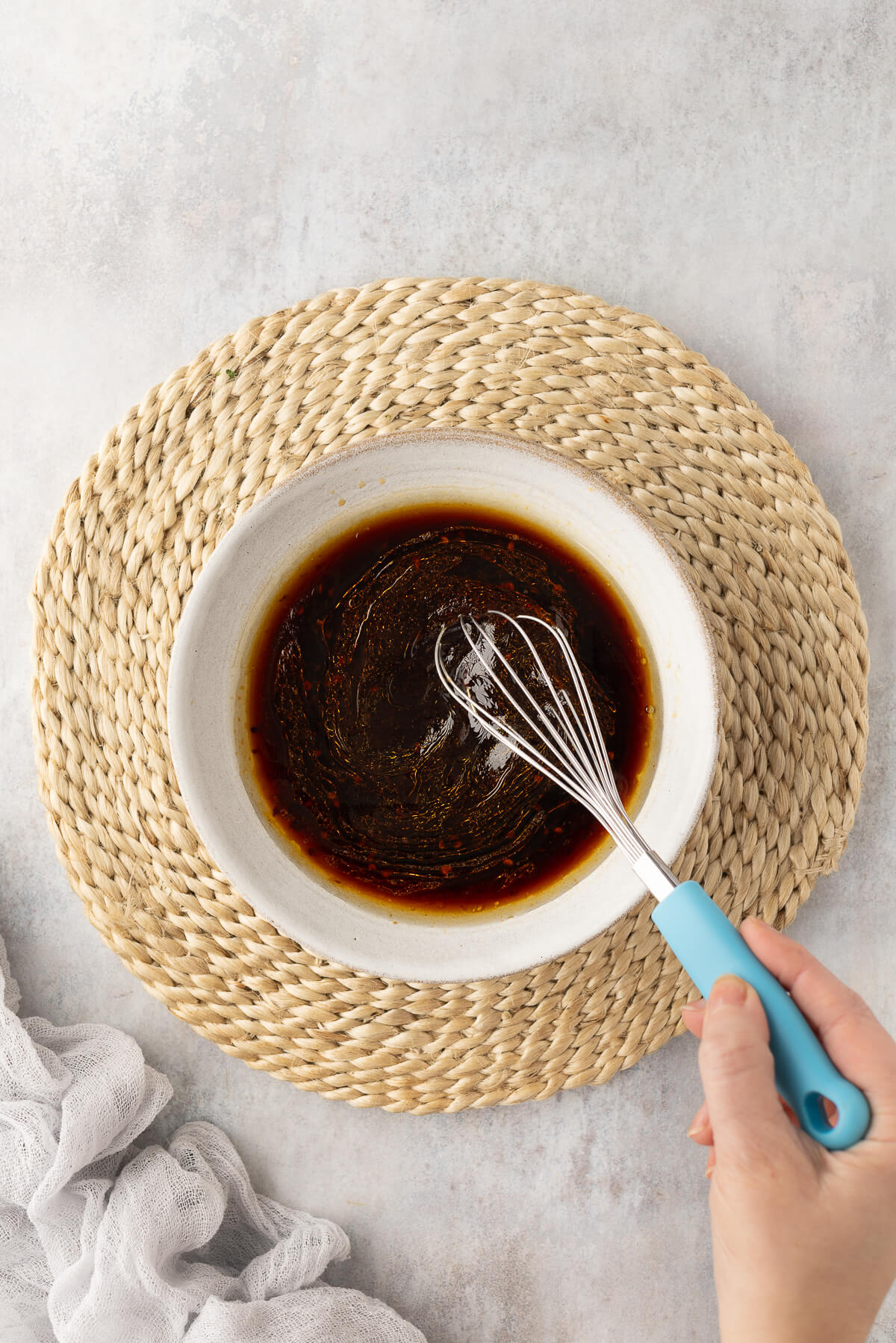 A spicy Asian chili garlic sauce is whisked together in a white bowl.