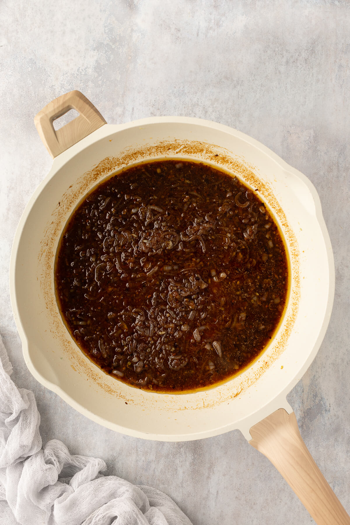 Spicy Asian chili garlic sauce for noodles cooks in a white ceramic pan.