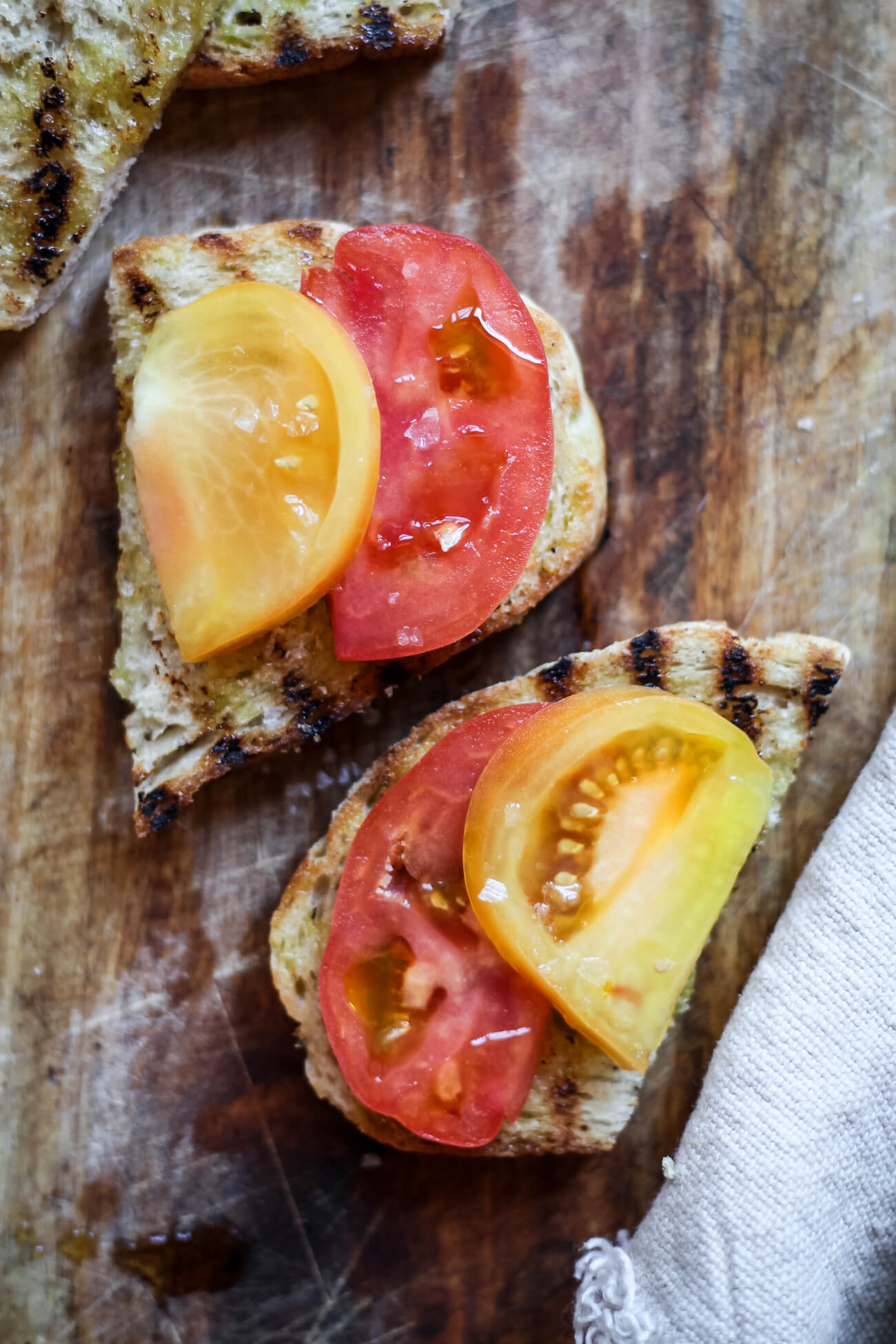 Two slices of grilled Tuscan bread topped with heirloom tomatoes, olive oil, and sea salt. 
