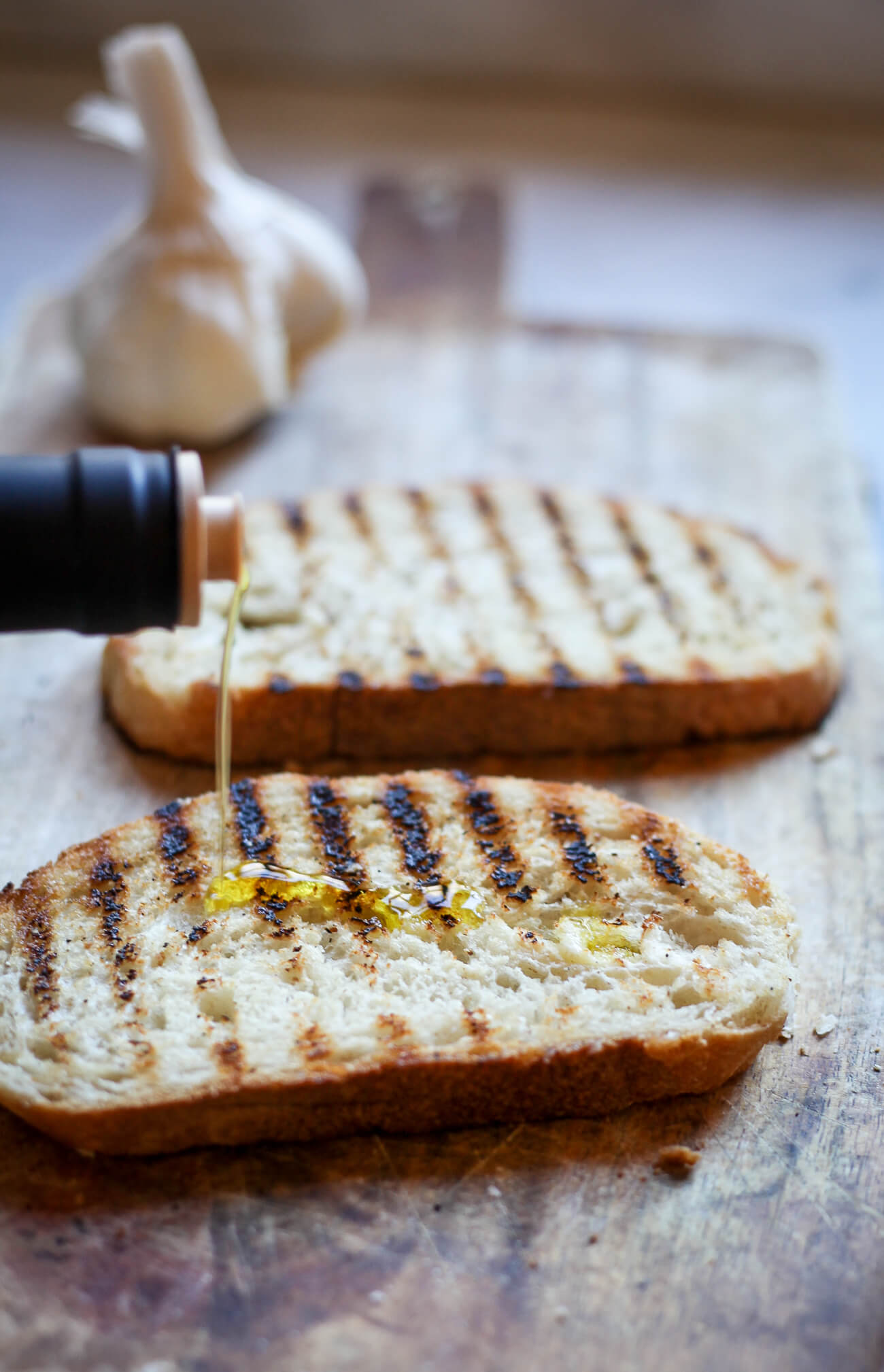 Extra virgin olive oil is drizzled over a piece of grilled Italian bread to make authentic bruschetta (fettunta).