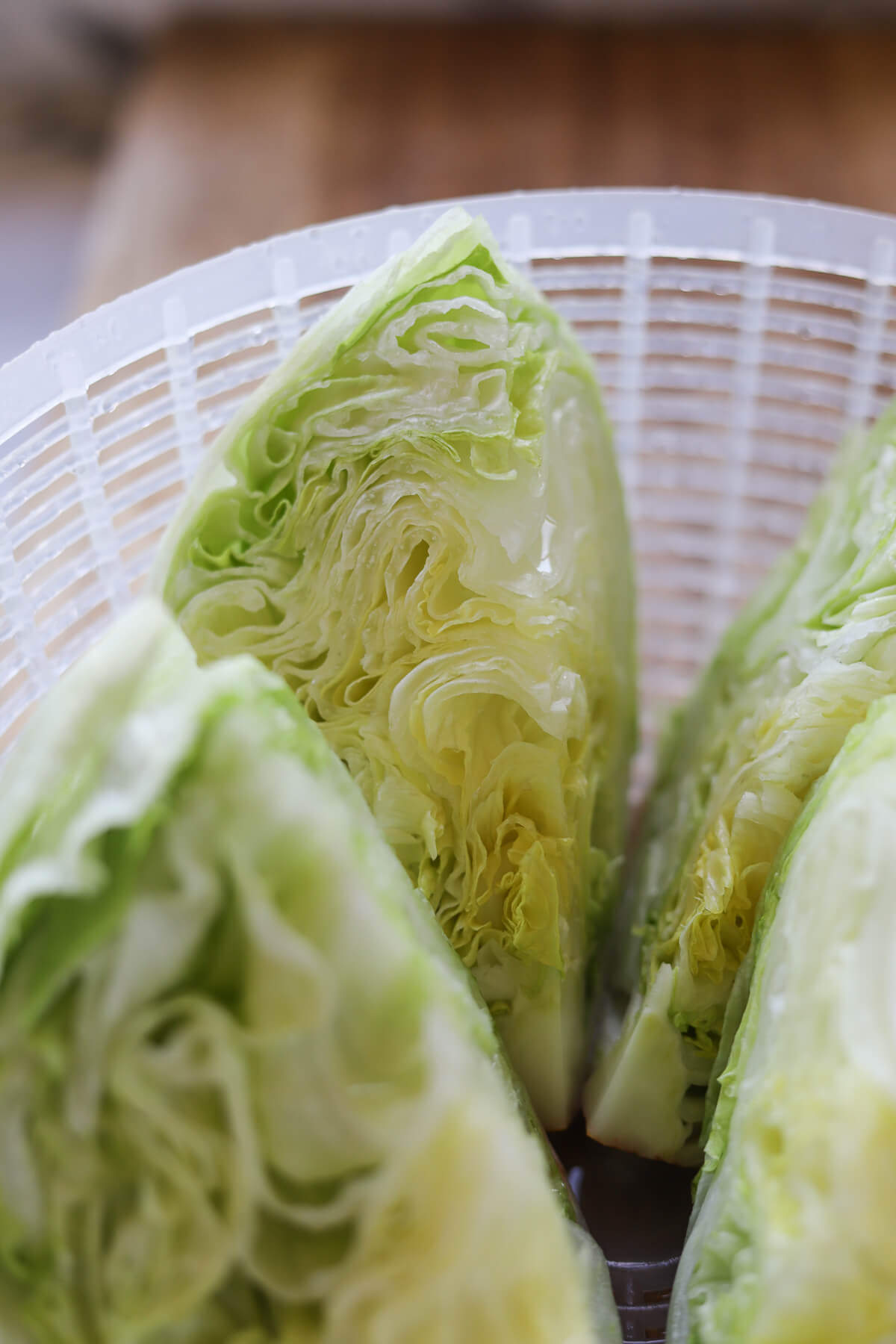 Freshly cut iceberg lettuce wedges resting in a salad spinner, ready to be dried for wedge salad.