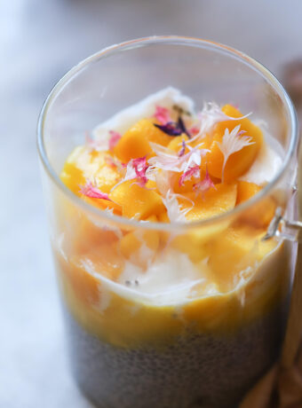 A beautiful photo of mango chia pudding with yogurt, mango puree and chunks and chia pudding at the bottom.