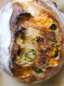 Close-up overhead photo of a loaf of homemade jalapeno cheddar sourdough bread.