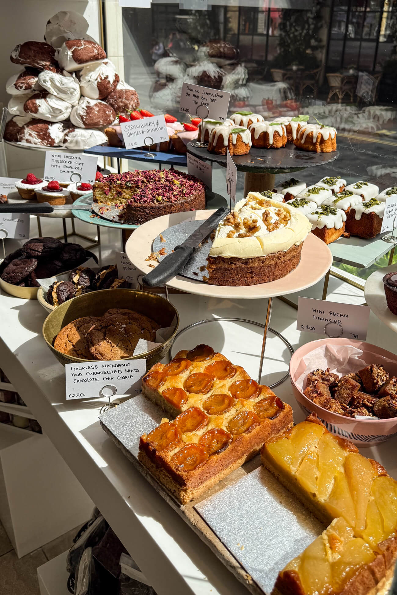 An array of beautiful desserts in the window of Ottolenghi in Marylebone. Cakes, cookies, and meringues all look delicious. 
