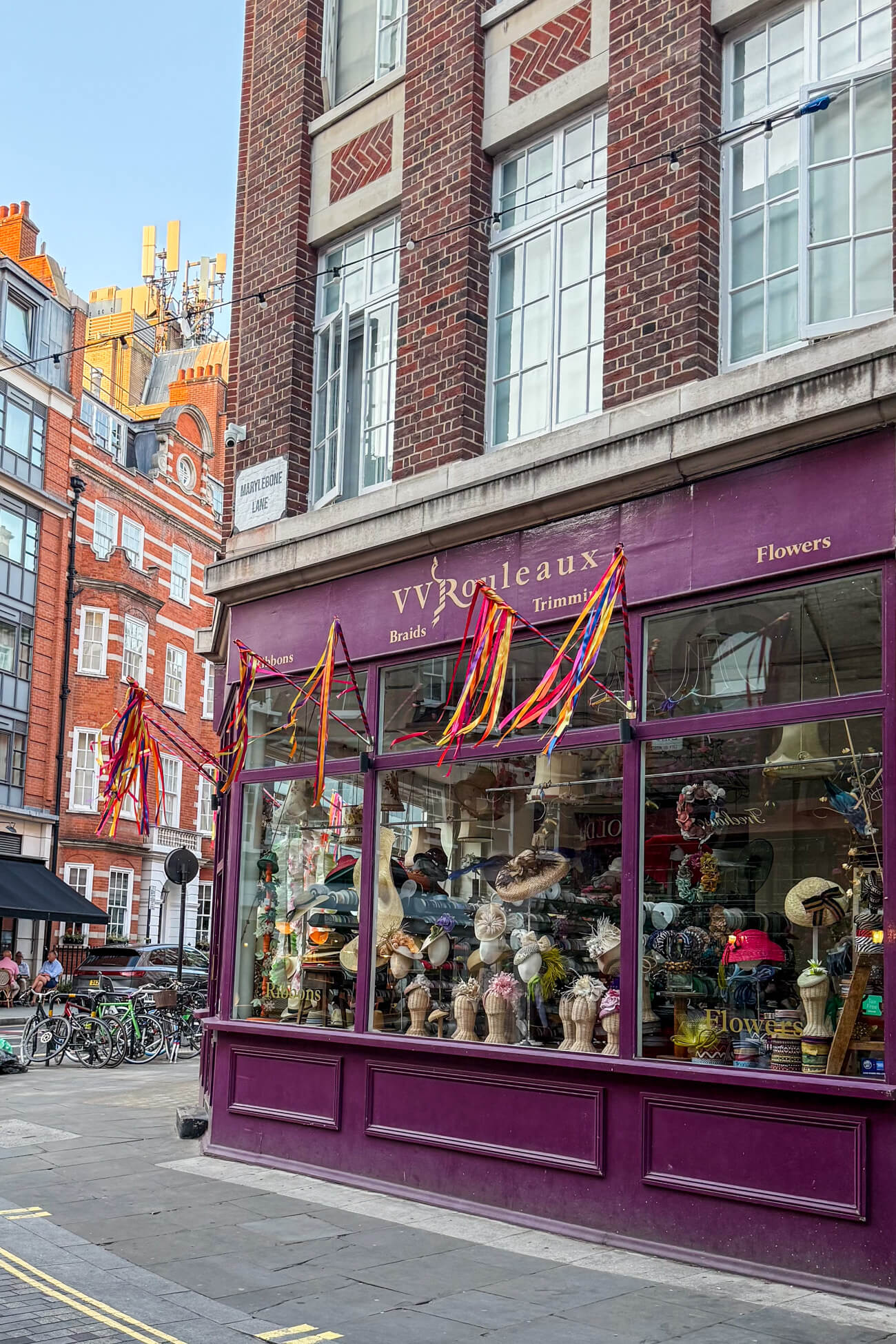 The outside of a classic Marylebone shop: VV Rouleaux, with proper English headbands and Ascot Hats. Ribbons adorn the front of the shop on Marylebone Lane.