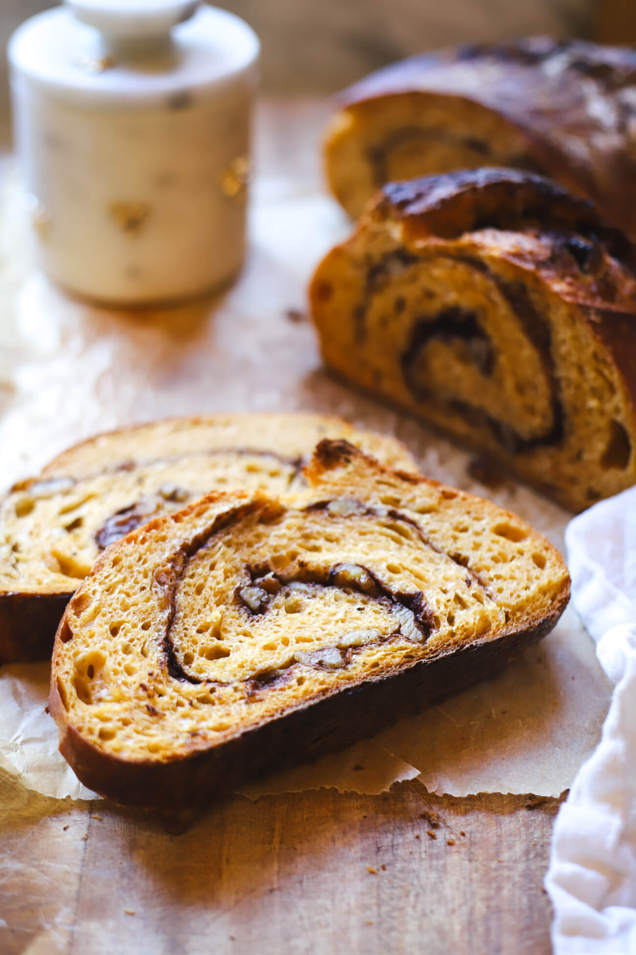 Sliced Pumpkin Sourdough Bread with Cinnamon Swirl Sliced pumpkin sourdough bread showing cinnamon sugar swirl and walnuts on parchment paper