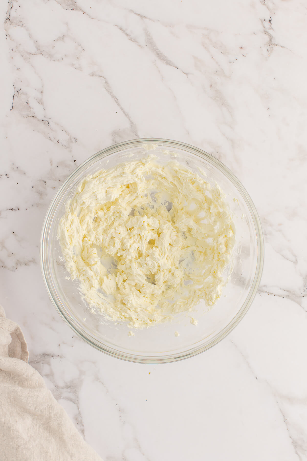 A bowl of whipped ricotta on a marble surface.