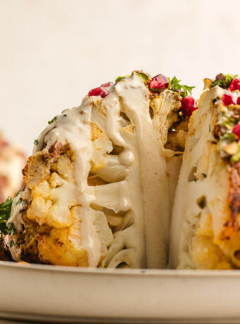 Whole roasted cauliflower with wedge removed. Topped with tahini dressing, pomegranate and pistachios.