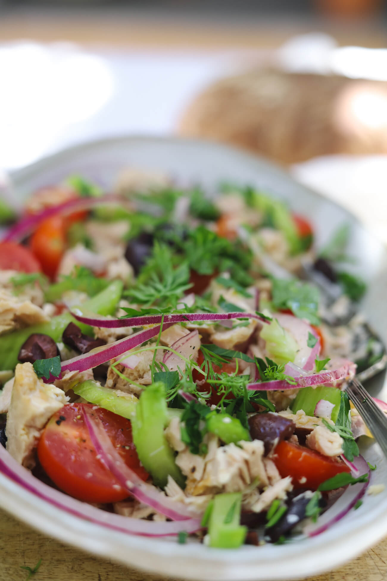 Mediterranean Tuna Salad Mediterranean tuna salad made with albacore tuna, cherry tomatoes, kalamata olives, celery, red onion, and fresh parsley in a white bowl.