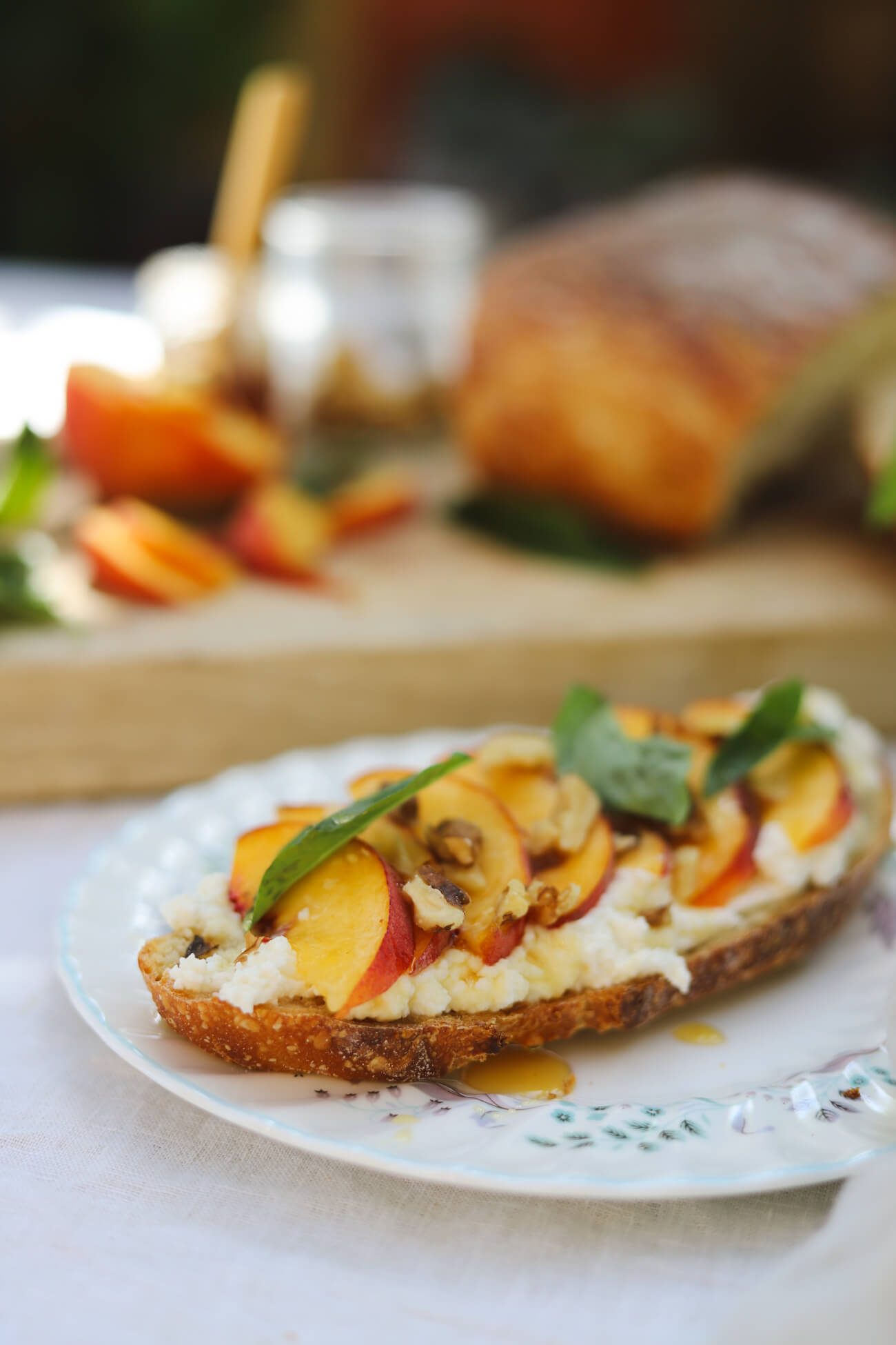 Peach Ricotta Toast Recipe Peach ricotta toast with whipped honey ricotta, fresh peaches, basil, walnuts, and honey on homemade sourdough.