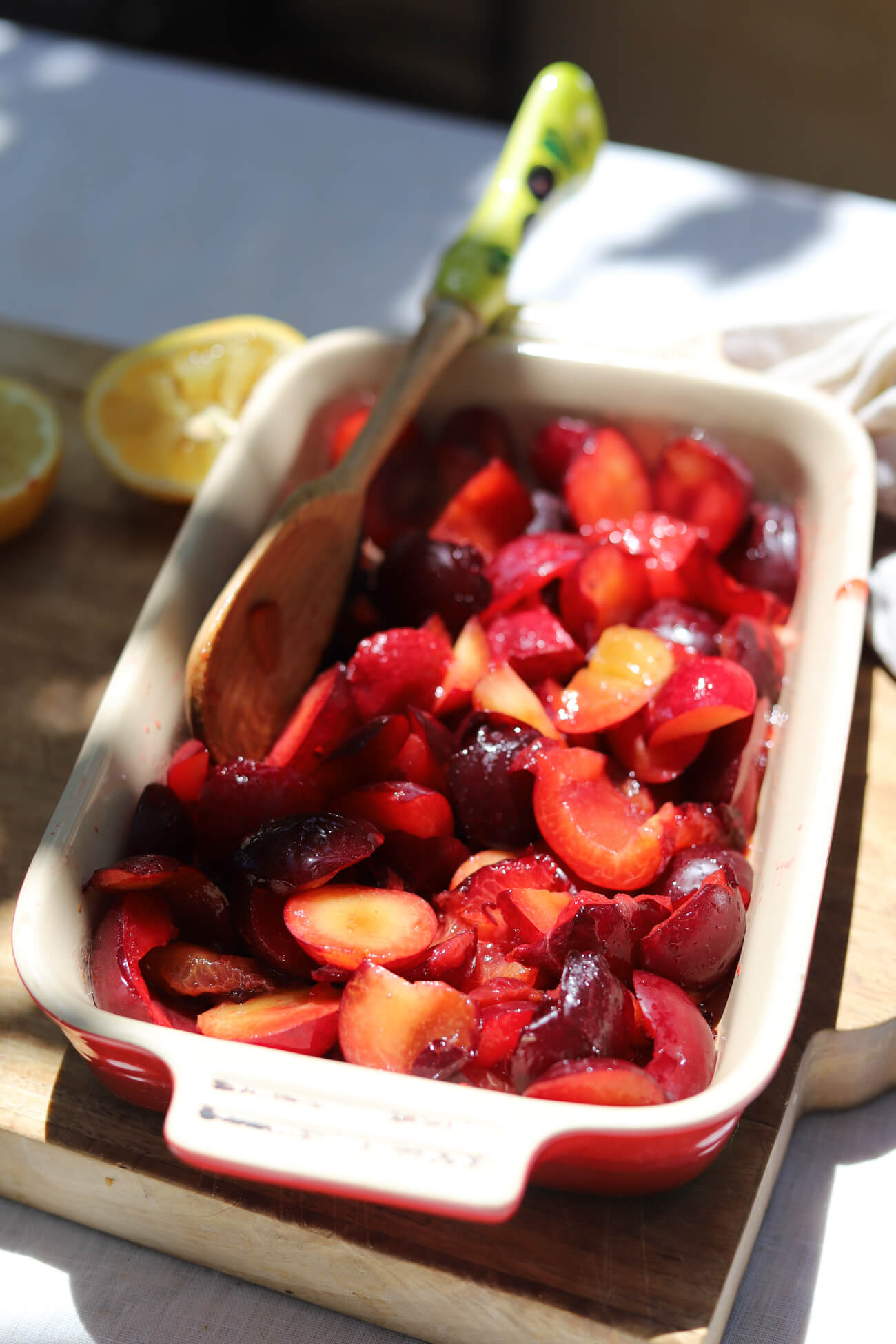 Plums Before Roasting for Plum Compote Fresh plums tossed with maple syrup and lemon juice in a baking dish before roasting for plum compote
