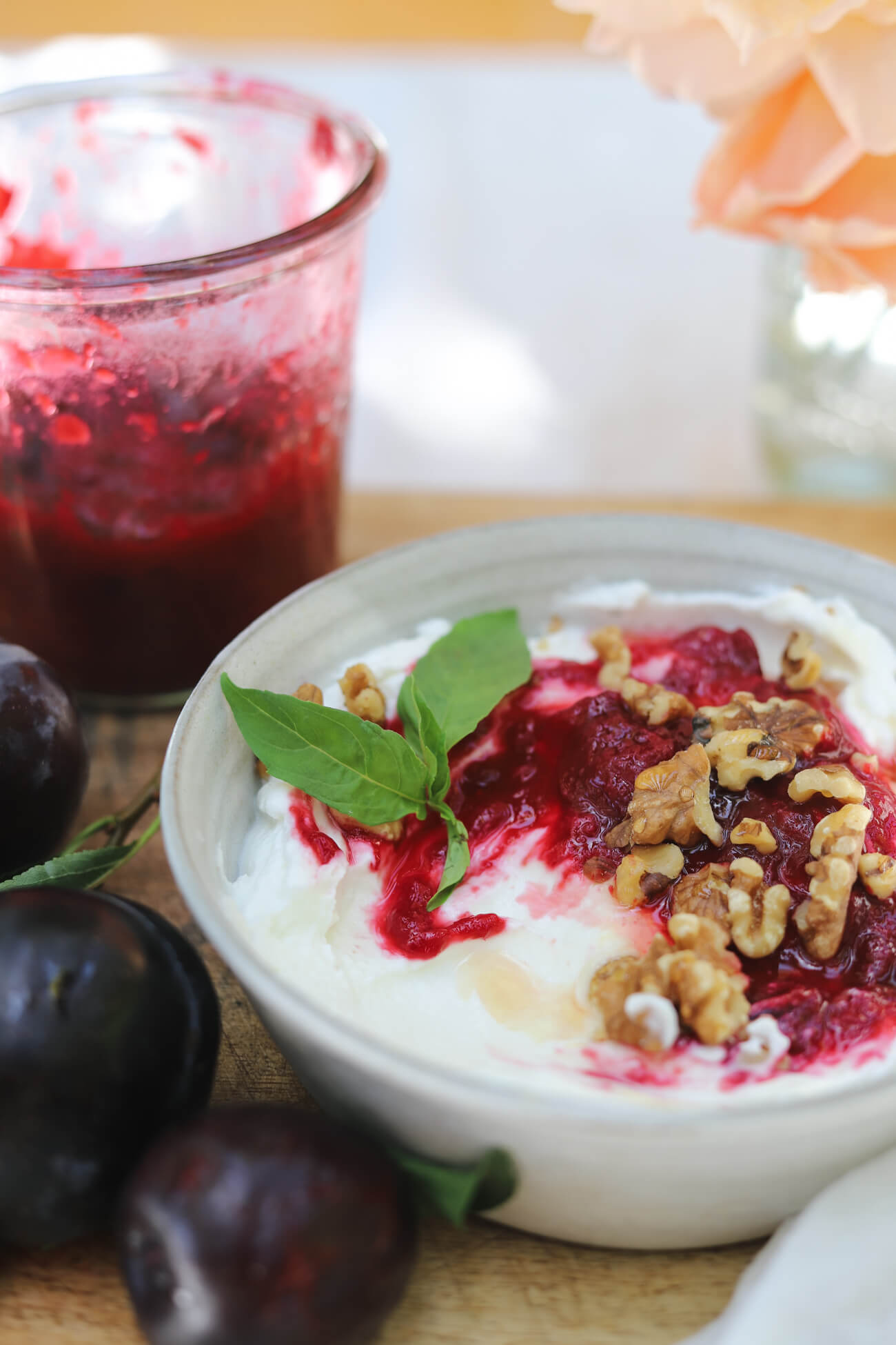 Greek Yogurt Bowl with Roasted Plum Compote Greek yogurt bowl topped with roasted plum compote and walnuts beside fresh plums and a jar of compote