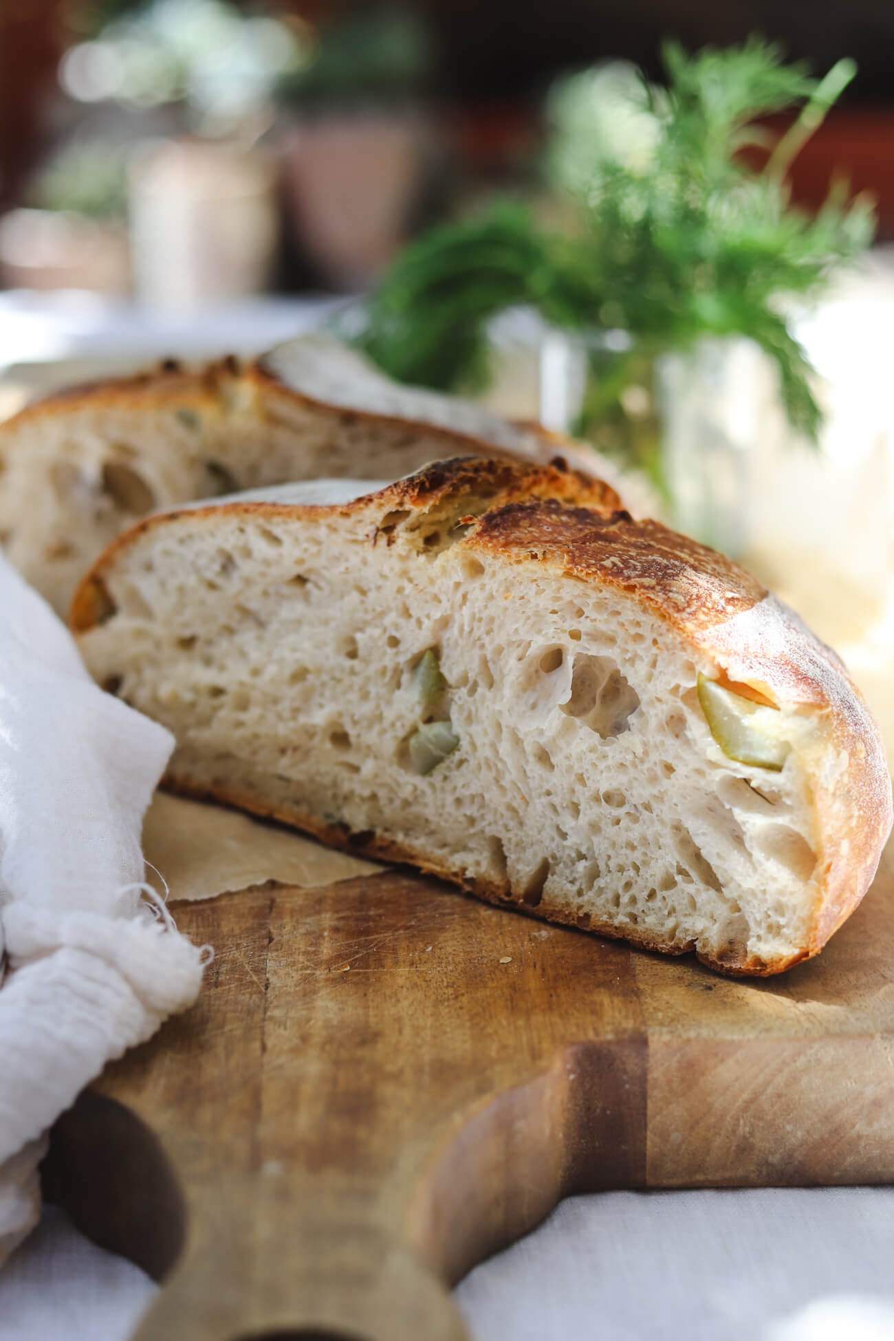 Dill Pickle Sourdough Bread Sliced dill pickle sourdough bread with chopped pickles and fresh dill on a cutting board.