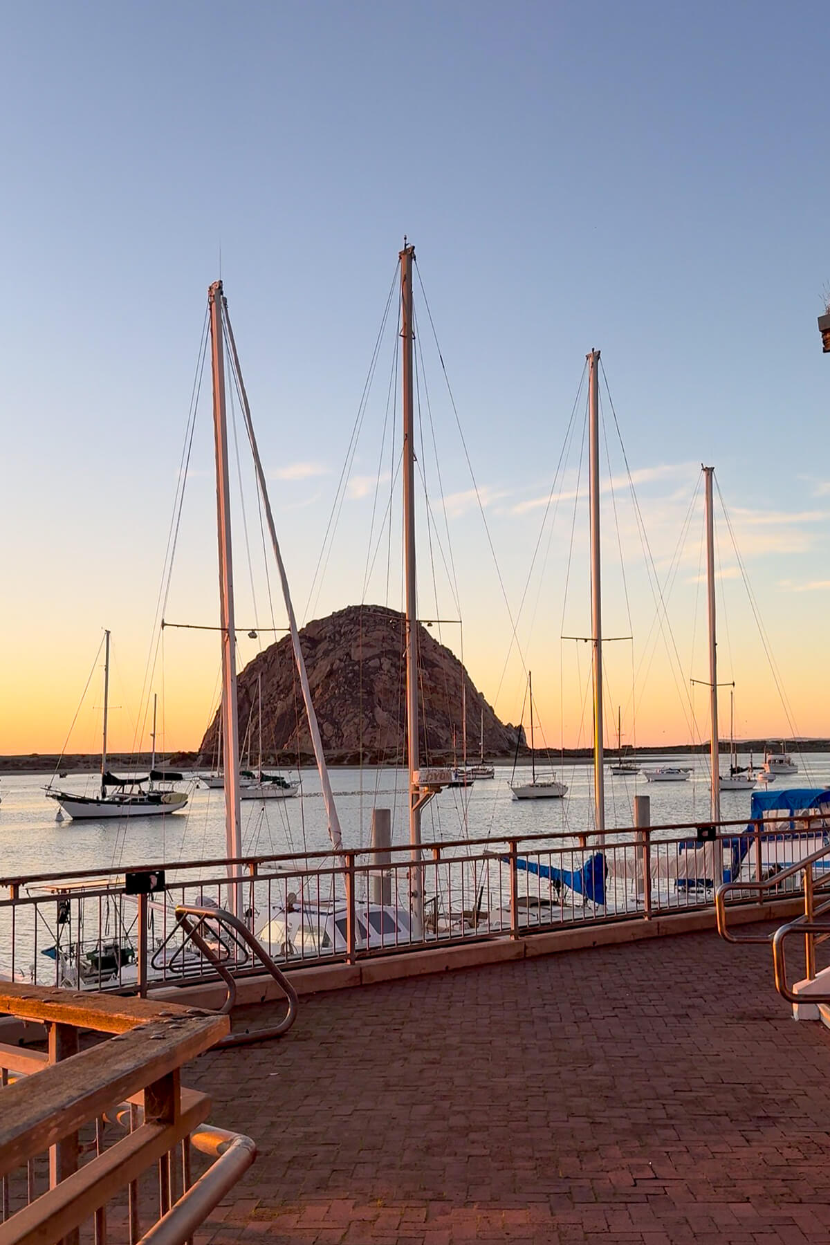 View of Morro Rock at Sunset from the Embarcadero Sailboats in Morro Bay Harbor with Morro Rock at sunset in Morro Bay, California. View from the Embarcadero.