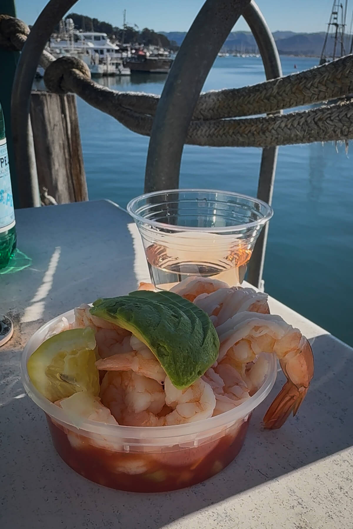 Morro Bay Embarcadero Seafood A shrimp cocktail topped with avocado and a glass of rose wine on a waterfront table in the Embarcadero in Morro Bay, CA.