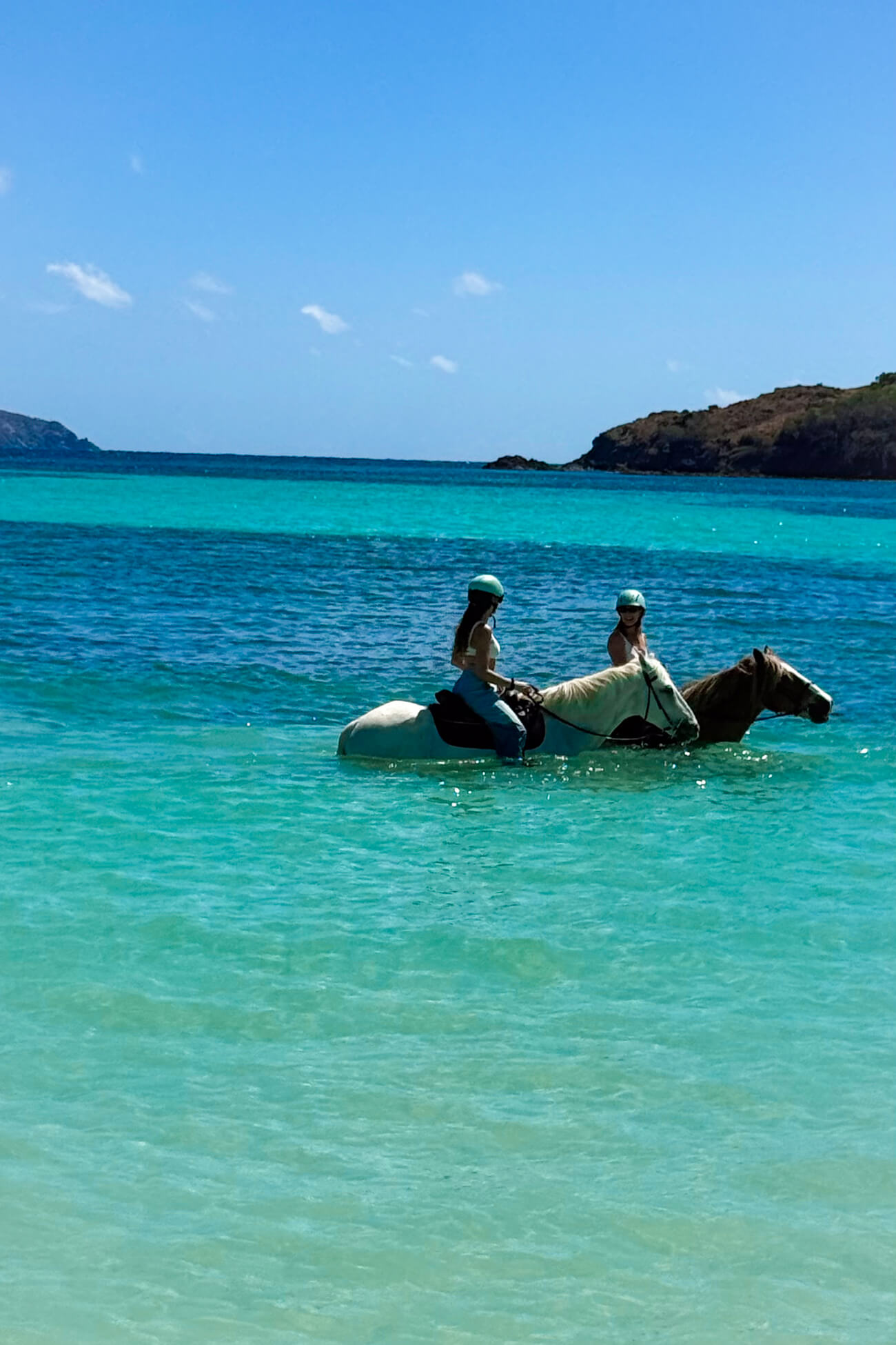 Horseback Riding in Mustique Marina Delio and friend horseback riding through the turquoise Caribbean Sea off Mustique Island, St. Vincent and the Grenadines.