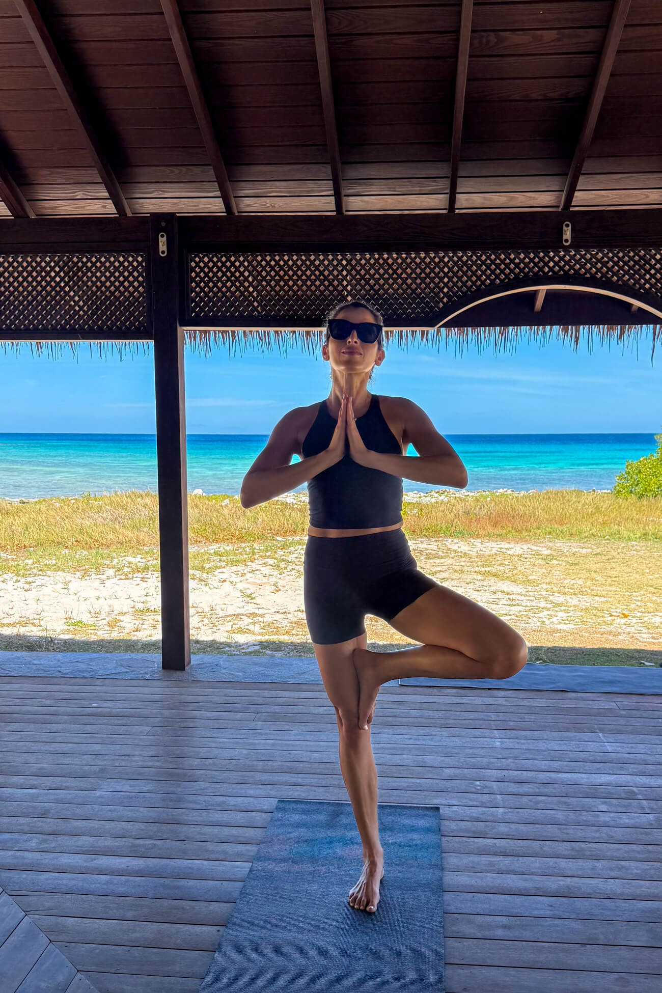 Beach Yoga in Mustique Island Marina Delio practicing yoga in an open-air pavilion overlooking the turquoise Caribbean Sea on Mustique Island.