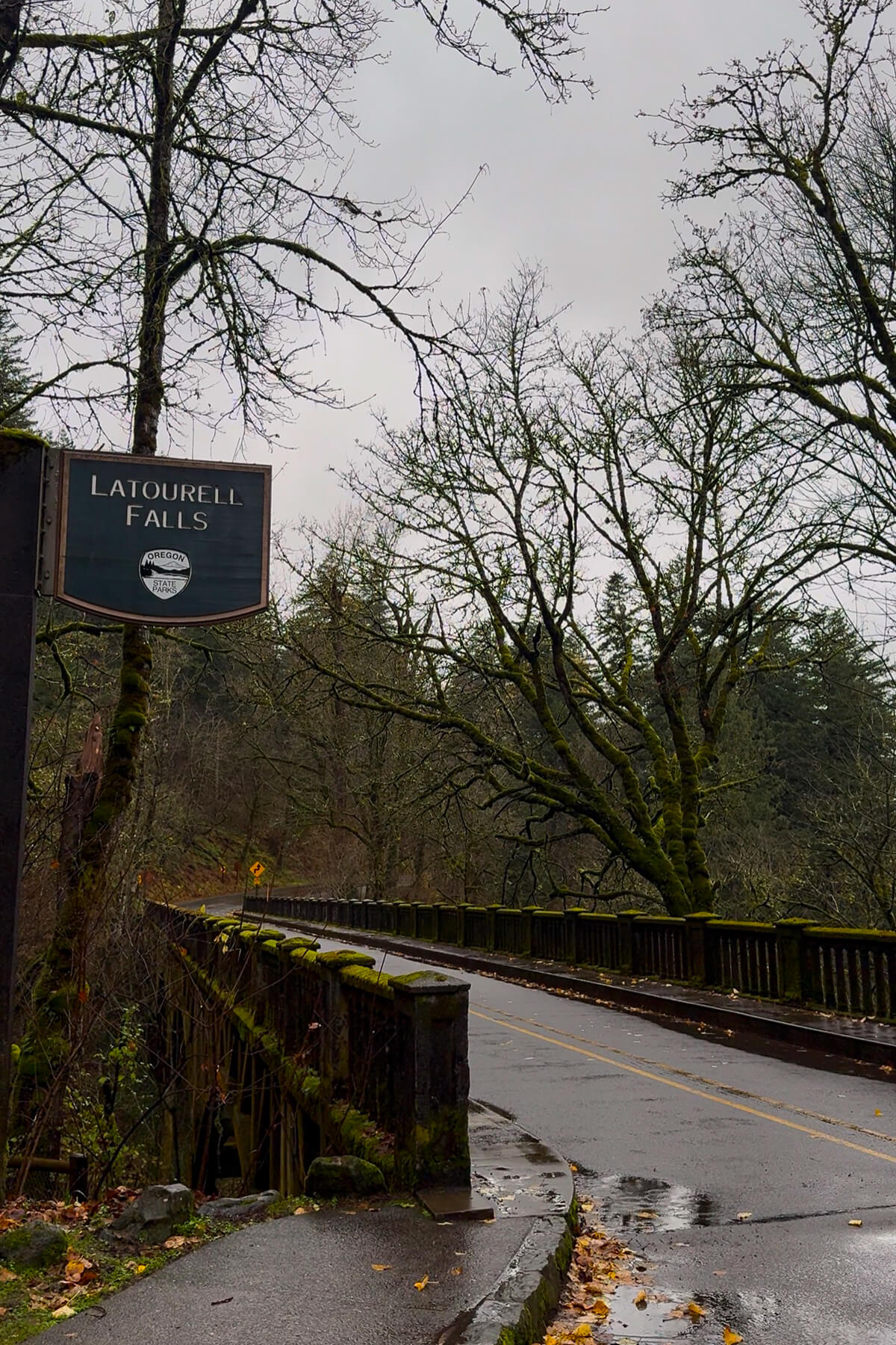 Latourell Falls The sign for Latourell Falls on the Columbia River Gorge in Oregon. Moss covers the bridge on the historic road.
